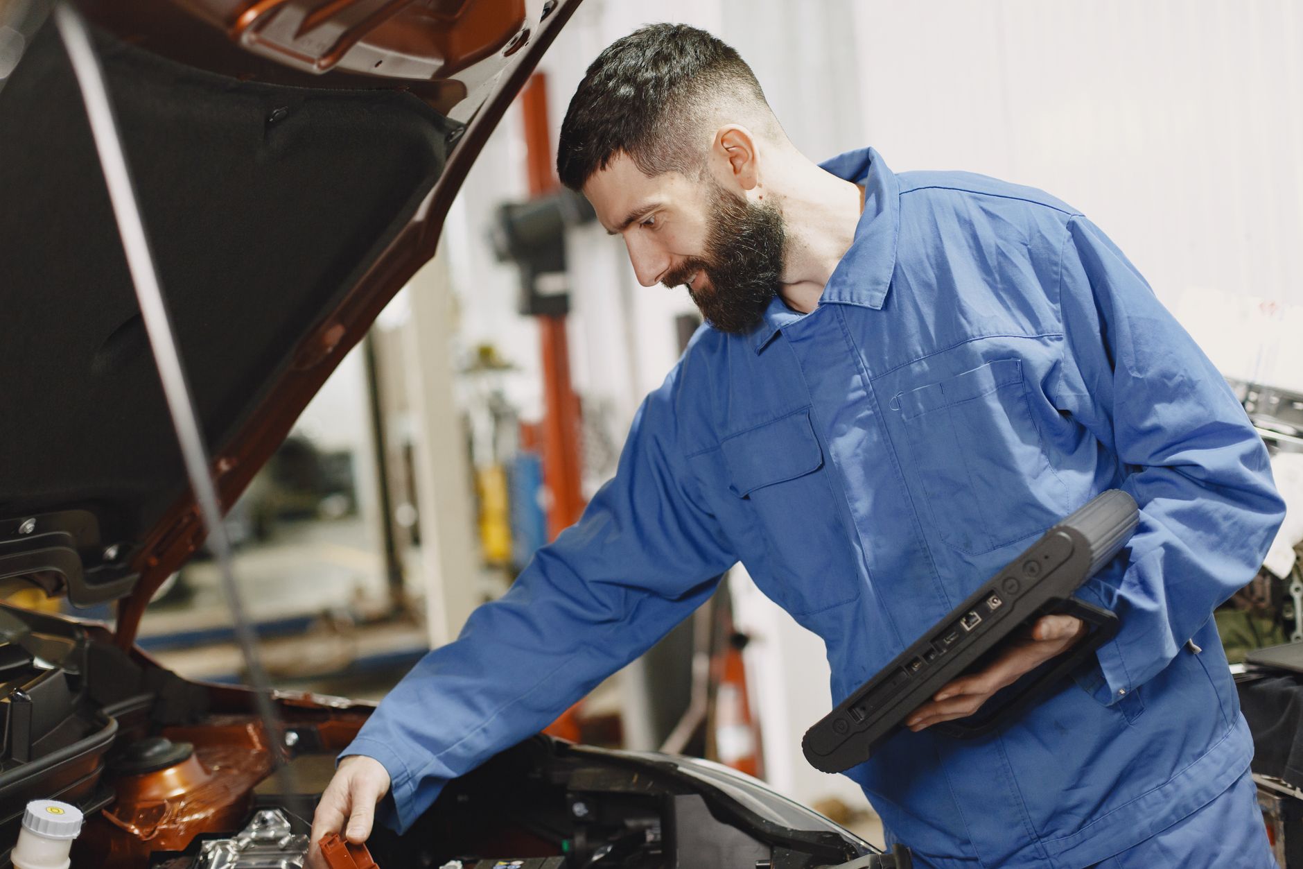 Mechanic in coveralls inspecting a car engine