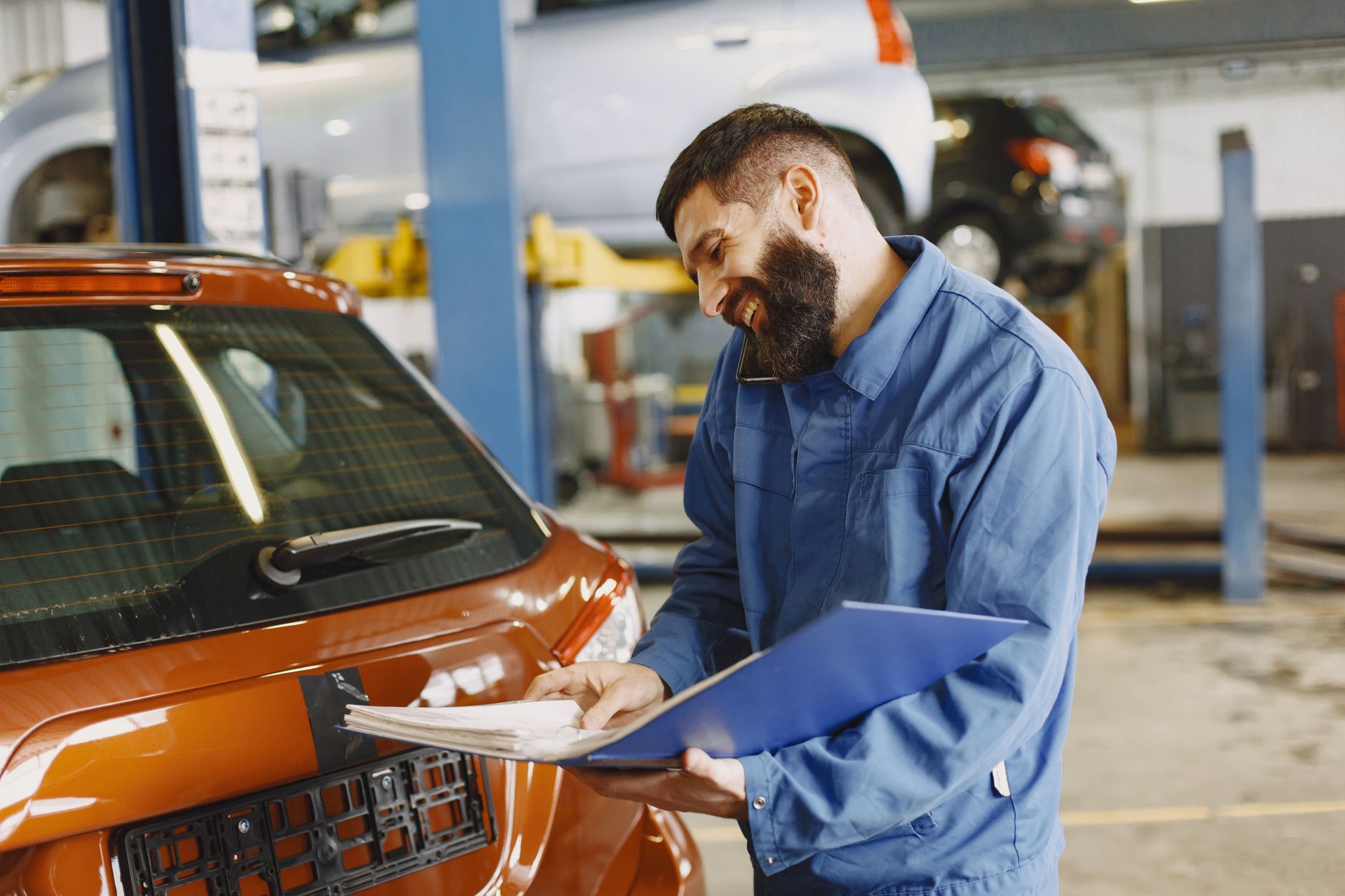 Smiling mechanic inspecting a car in a service garage